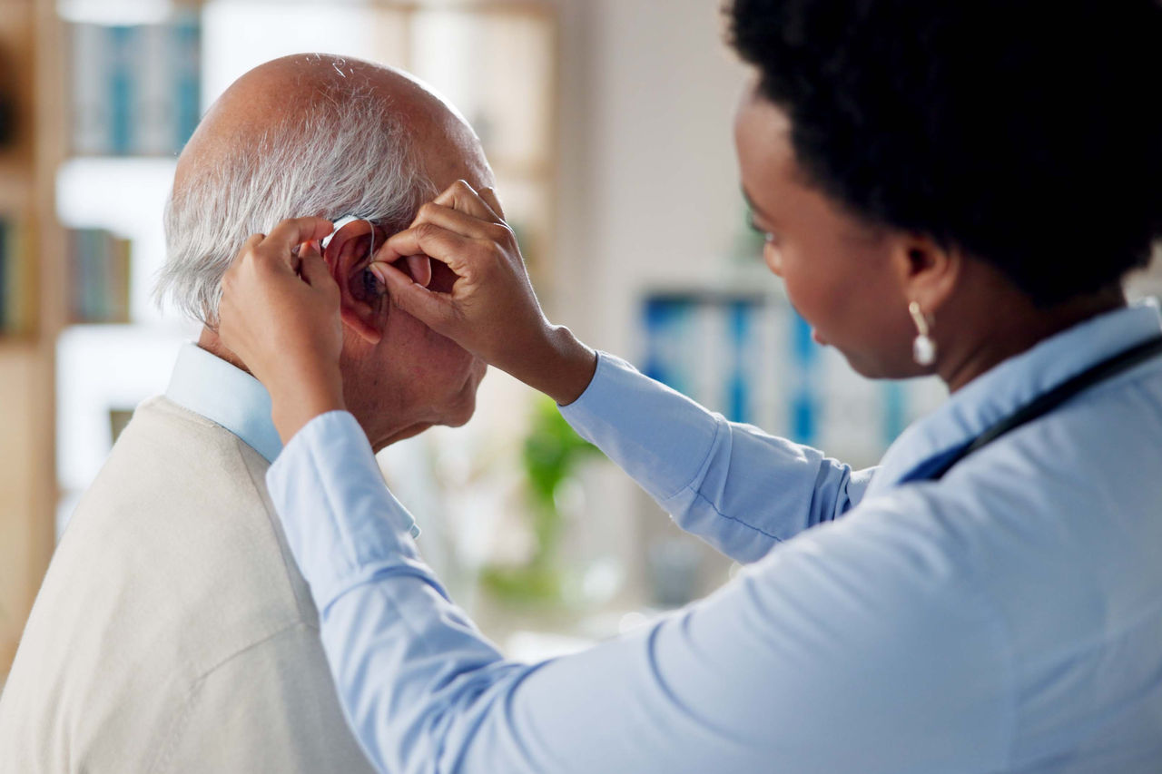Senior getting fitted for a hearing aid in a lab.